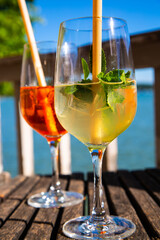 Hugo and Aperol Sprizz together on a wooden table, with the Ammersee in the background