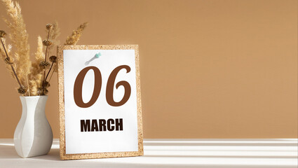 march 6. 6th day of month, calendar date.White vase with dead wood next to cork board with numbers. White-beige background with striped shadow. Concept of day of year, time planner, spring month