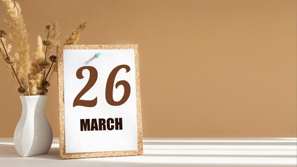 march 26. 26th day of month, calendar date.White vase with dead wood next to cork board with numbers. White-beige background with striped shadow. Concept of day of year, time planner, spring month