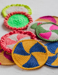 Many bright clolored spiral coasters for hot. Eco friendly crochet coaster with tunisian pattern. Home decor concept.