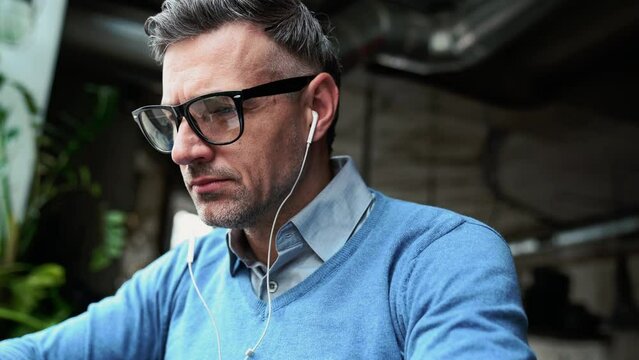 Pensive grey haired man working on laptop while sitting in cafe