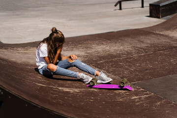 Active child girl after fall from penny board injured, sitting and feel pain on sport ramp on skate...