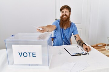 Young redhead politic party worker smiling happy holding vote at electoral college.