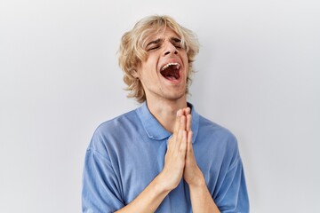 Young modern man standing over isolated background begging and praying with hands together with...