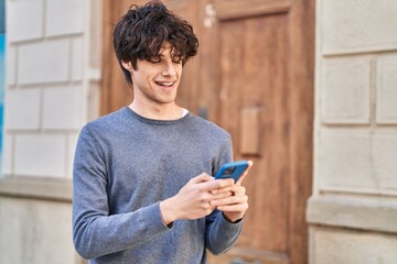 Young hispanic man smiling confident using smartphone at street