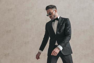 portrait of handsome elegant groom in black tuxedo looking down side