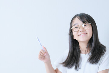 Obraz premium ボールペンを持って眼鏡をかけた笑顔の少女