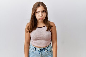Young brunette woman standing over isolated background puffing cheeks with funny face. mouth inflated with air, crazy expression. - obrazy, fototapety, plakaty