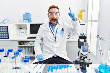 Fototapeta premium Middle age man working at scientist laboratory pointing finger up with successful idea. exited and happy. number one.