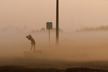 A biker doing yoga stretching facing the sunrise in the haze