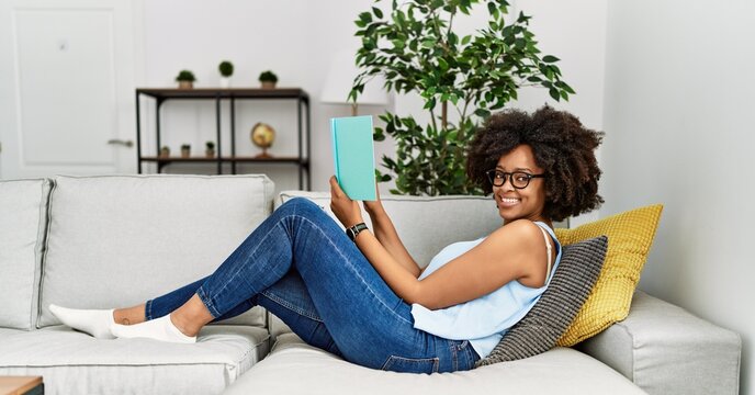 Young african american woman smiling confident reading book at home