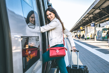 Young business woman standing on train door peeking out looking for somebody in railway station - Potrait of beautiful traveler woman getting on the train - Travelling concept