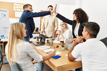 Two workers smiling happy high five during meeting at the office.