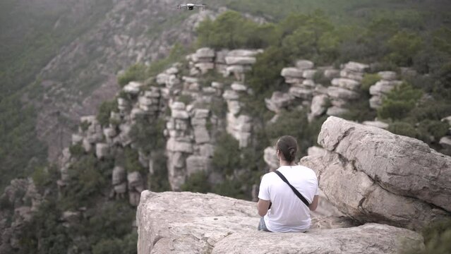Influencer caucasian man flimming with a drone siting on a mountain