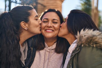 Three woman mother and daughters standing together and kissing at street