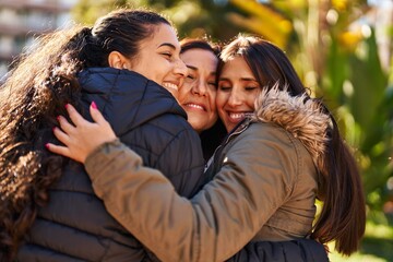 Three woman mother and daughters hugging each other at park