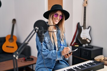 Fototapeta na wymiar Young woman musician smiling confident composing song at music studio