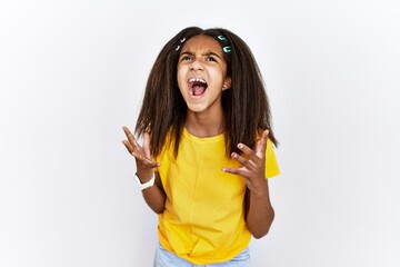 Young african american girl standing over white isolated background crazy and mad shouting and...