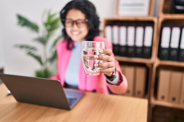 Young latin woman business worker using touchpad drinking water at office