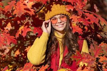 Teen child girl on autumn fall leaves background. positive kid in sunglasses at autumn leaves on natural background