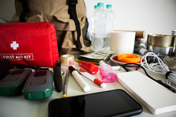 Emergency backpack equipment organized on the table. Documents, water,food, first aid kit and...