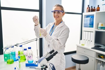 Naklejka premium Young blonde woman wearing scientist uniform working at laboratory