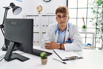 Obraz premium Young caucasian doctor man working at the clinic relaxed with serious expression on face. simple and natural looking at the camera.