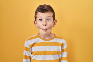Young caucasian kid standing over yellow background making fish face with lips, crazy and comical gesture. funny expression.