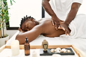 Obraz na płótnie Canvas African american woman reciving back massage at the clinic.