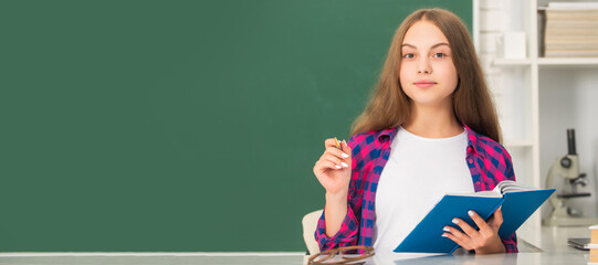 smiling child making notes in notebook. back to school. teen girl ready to study. Portrait of schoolgirl student, banner header. School child face isolated panorama background with copy space.