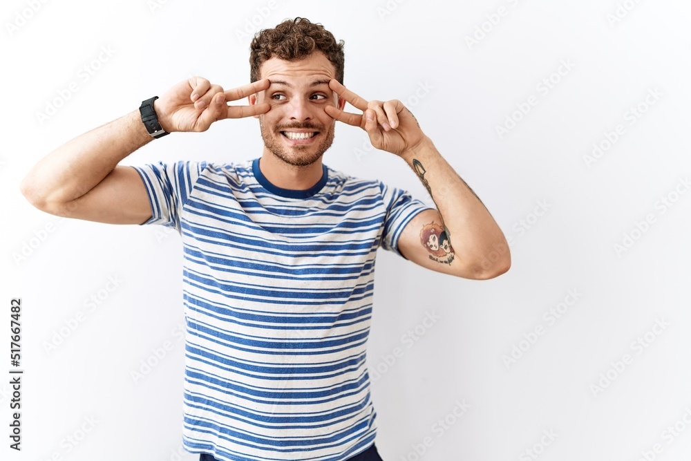 Poster Handsome young man standing over isolated background doing peace symbol with fingers over face, smiling cheerful showing victory