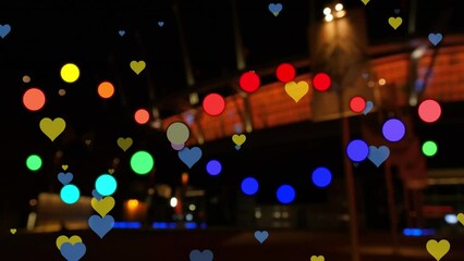 Animation of dots and hearts floating over blurred night cityscape - Powered by Adobe