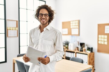 Young hispanic businessman smiling happy standing at office.