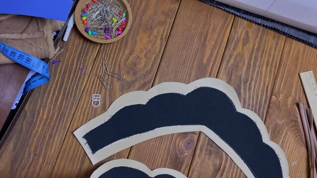 Female's hands lay out cloth in form of ethnic Slavic crown on wooden table. Seamstress and her workplace. Headdress from eco-leather and adhesive woven interlining fabric.