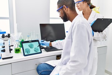 Man and woman scientist partners looking embryo image on touchpad at laboratory