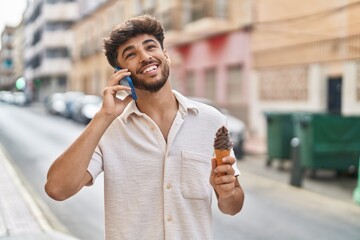 Young arab man talking on the smartphone eating ice cream at street