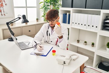 Obraz premium Young arab man wearing doctor uniform writing on document analysing urine test tube at clinic
