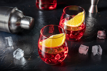 Campari aperitif garnished with fresh oranges, with a cocktail shaker, ice cubes, and a jigger and...