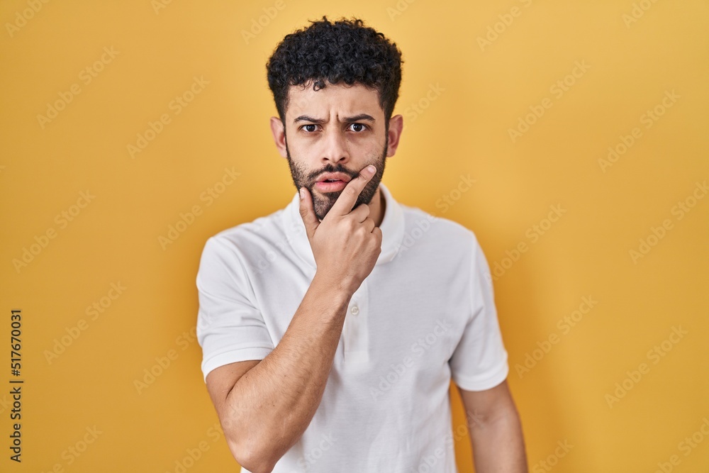 Poster arab man standing over yellow background looking fascinated with disbelief, surprise and amazed expr