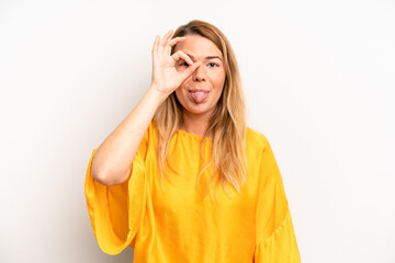 blonde pretty woman smiling happily with funny face, joking and looking through peephole, spying on...