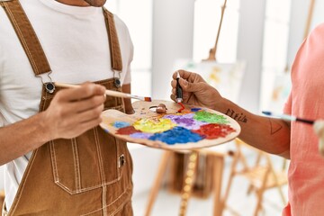 Two hispanic men couple mixing color on palette at art studio