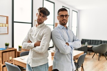 Two hispanic men business workers standing with arms crossed gesture at office