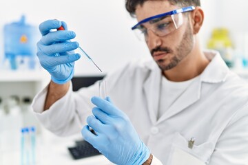 Handsome hispanic man working as scientific holding test tube at laboratory
