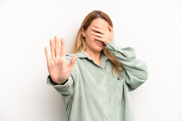 blonde pretty woman covering face with hand and putting other hand up front to stop camera,...