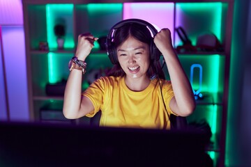 Chinese woman streamer using computer with winner expression at gaming room