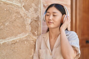 Chinese woman smiling confident listening to music at street