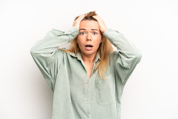 blonde pretty woman feeling horrified and shocked, raising hands to head and panicking at a mistake