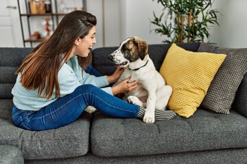Young woman hugging dog sitting on sofa at home