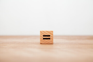 =の記号。イコール。等しい。同じ。木製ブロックに書かれている。黒い文字。木製テーブルの背景。