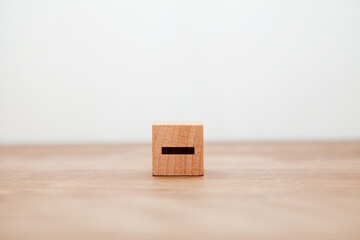 -の文字。マイナス。木製ブロックに書かれている。黒い文字。木製テーブルの背景。